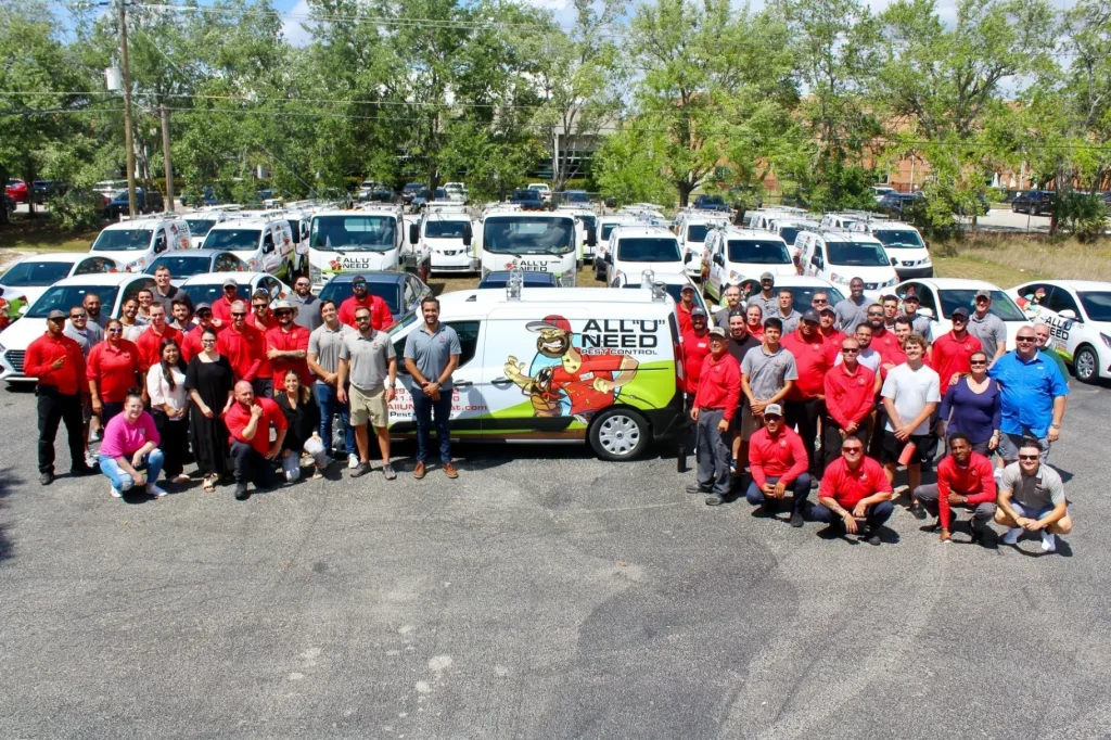 All U Need Pest Control team posing in front of branded service vehicles